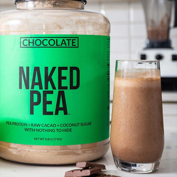 A 2 Pack of Naked Nutrition Chocolate Pea Protein Isolate 1LB sits next to a glass of chocolate smoothie on a kitchen counter.